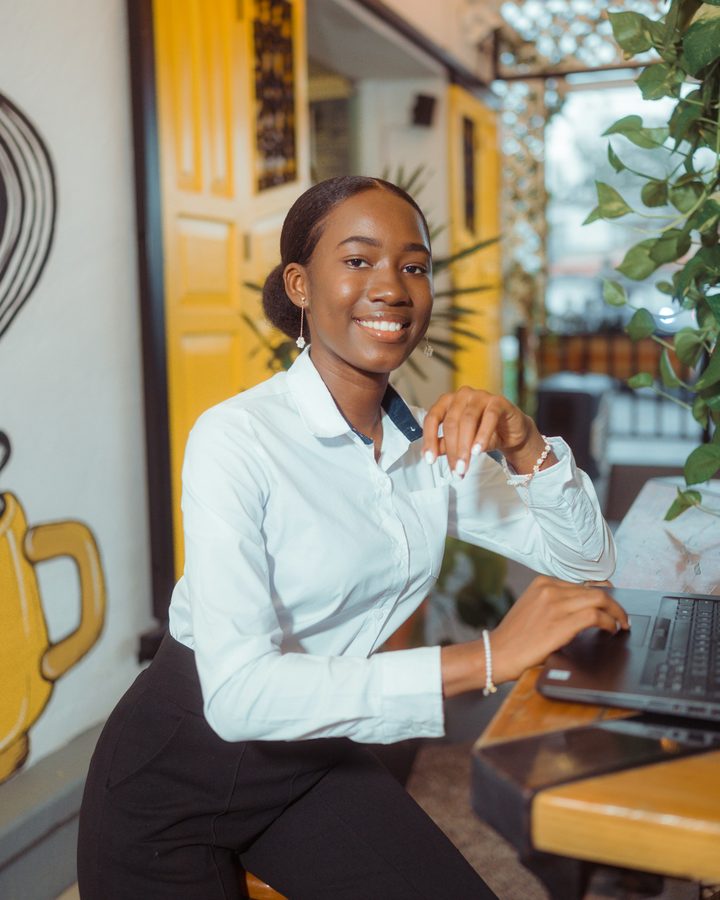 Dona de café sorrindo no balcão, ao lado do notebook